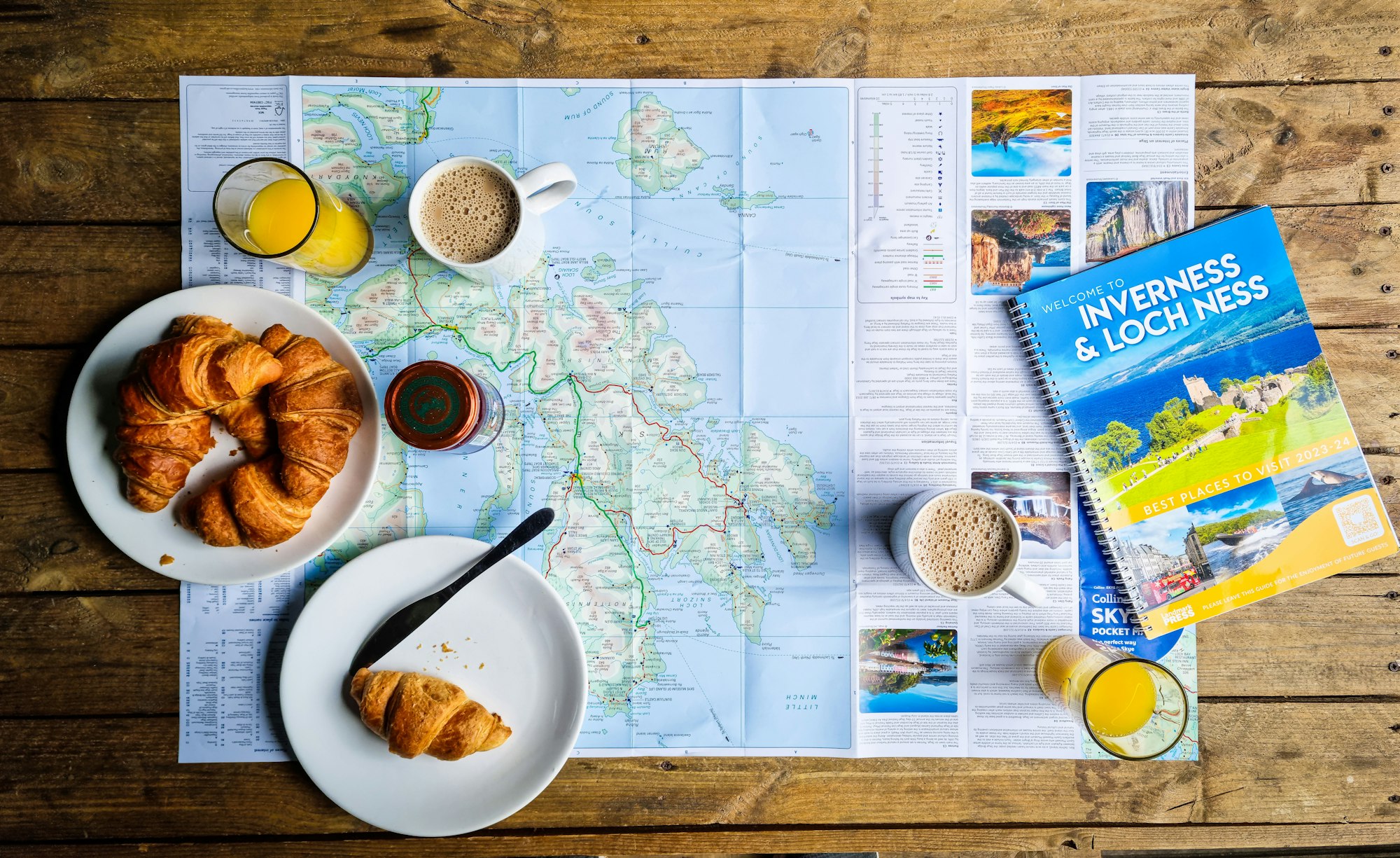 Guide, carte du monde, croissant et café